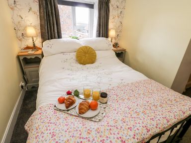 A bedroom with a bed set with floral bedding and a breakfast tray at The Lodge in Stainsacre near Whitby
