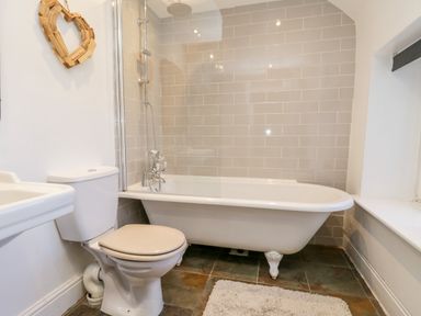 A bathroom with a toilet sink and clawfoot bathtub with shower at The Lodge in Stainsacre near Whitby
