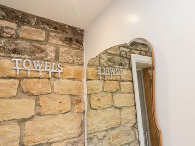 A stone wall with a metal towel rack and a mirror reflecting the wall at The Lodge in Stainsacre near Whitby