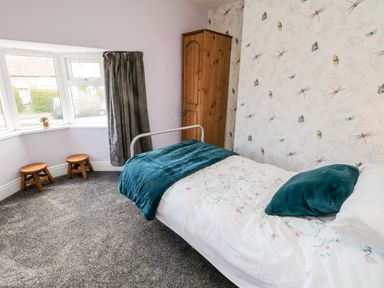 A bedroom with a single bed wardrobe two stools and a bay window at The Lodge in Stainsacre near Whitby