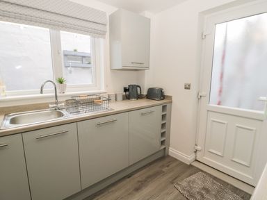 A kitchen with a sink dish rack kettle toaster and cabinets at Pebble Cove in Amble