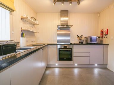 A kitchen with a black countertop stove oven microwave and sink at Apple Barn in Crantock