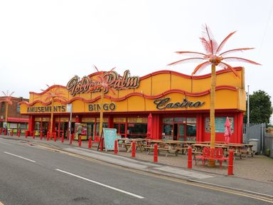 A street view of a building with signs for amusements bingo and casino and artificial palm trees outside at 98 Cherry Park in Chapel St Leonards
