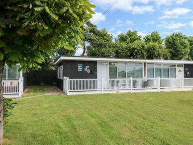 A single story house with a white fence and green lawn in front at 98 Cherry Park in Chapel St Leonards