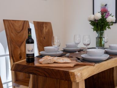 A dining table set with white dishes glasses bread and a wine bottle at The Belfry in Windermere