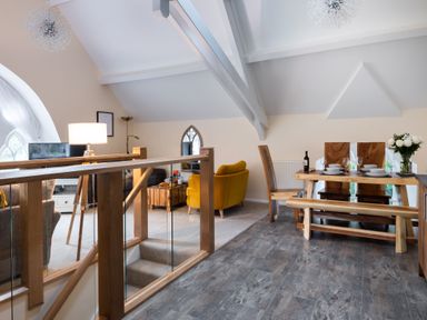 An open living and dining area with wooden furniture and a yellow armchair at The Belfry in Windermere