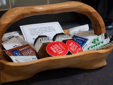 A wooden basket with various packets of food items and a note at The Belfry in Windermere
