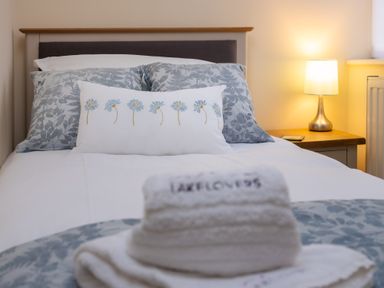 A bed with floral pillows and a lamp on a nightstand at The Belfry in Windermere