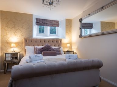 A bedroom with a bed pillows bedside tables and lamps at The Belfry in Windermere
