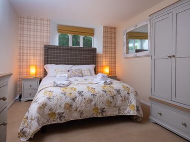 A bedroom with a double bed with floral bedding and towels on top at The Belfry in Windermere