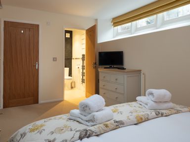 A bedroom with folded towels on a bed and a dresser with a television at The Belfry in Windermere