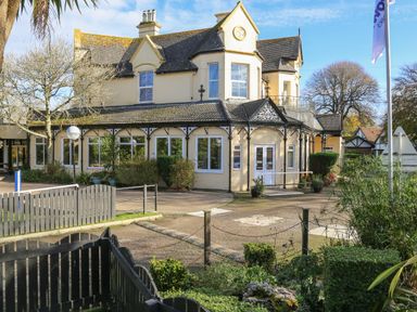 A large house with bay windows and a garden area with shrubs and potted plants at Miles Retreat in Hayle