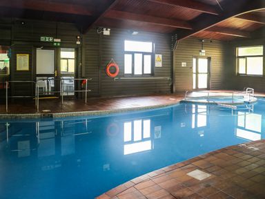 An indoor swimming pool with tiled flooring and windows at Miles Retreat in Hayle