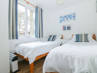 A bedroom with two single beds a window and a small bedside table at Miles Retreat in Hayle