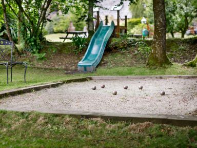 An outdoor area with a bocce ball court metal chair green slide and picnic table at The Roundhouse in Warbstow