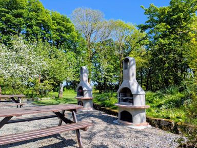 An outdoor area with grills and picnic tables at The Roundhouse in Warbstow