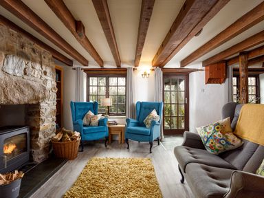 A living room with stone fireplace blue armchairs and a gray sofa at Little Leighs in Warbstow