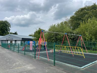 A playground with swings and a play structure at a school