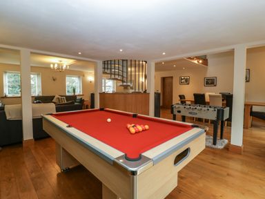 A room with a pool table with red felt a foosball table a dining table with chairs and a seating area with sofas at About Time Cottage in Parkend