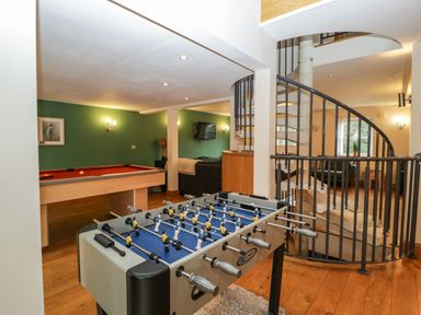 A games room with a foosball table and a pool table near a spiral staircase at About Time Cottage in Parkend
