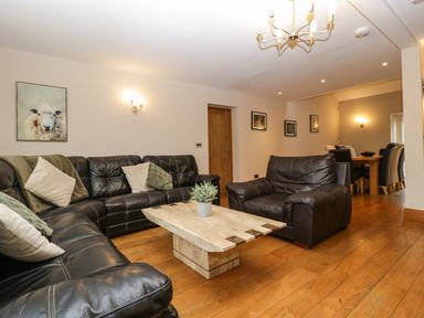 A living room with black leather sofas and a stone coffee table at About Time Cottage in Parkend