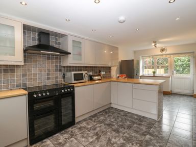 A kitchen with cabinets oven microwave refrigerator and a door leading outside at About Time Cottage in Parkend