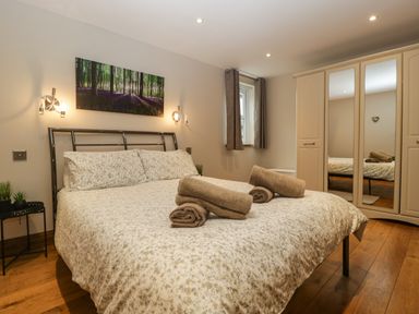A bedroom with a double bed with towels on the bed and a wardrobe with mirrored doors at About Time Cottage in Parkend