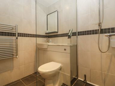 A bathroom with a toilet sink mirror shower and towel rack at About Time Cottage in Parkend