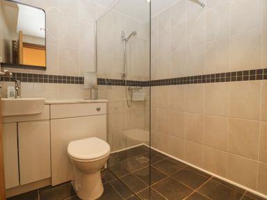 A bathroom with a toilet sink mirror and shower area at About Time Cottage in Parkend