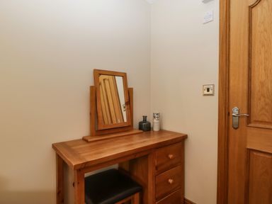 A wooden dressing table with a mirror and vases next to a wooden door at About Time Cottage in Parkend
