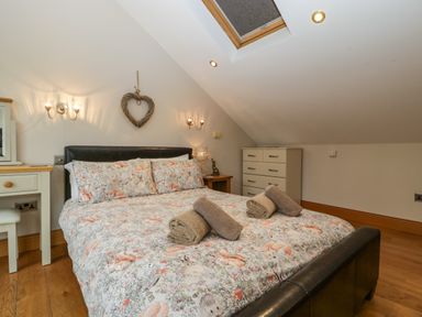 A bedroom with a bed with animal print bedding towels on bed wooden floor and chest of drawers at About Time Cottage in Parkend