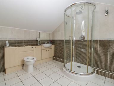A bathroom with a corner shower enclosure a toilet and a sink with cabinets at About Time Cottage in Parkend