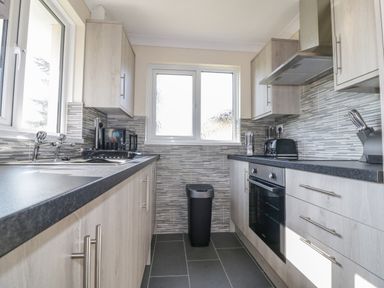 A kitchen with cabinets sink oven and a trash bin at Watergate Bay in Liskeard