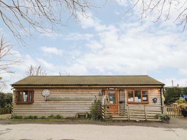 The exterior of Bretforton Community Shop a single story wooden building with windows and a door at Cotswold View 1 in Honeybourne