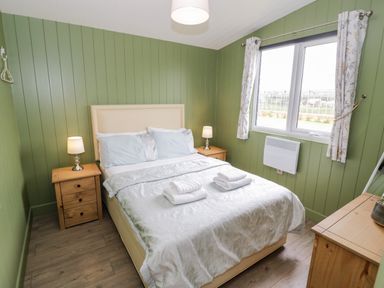 A bedroom with a bed two bedside tables with lamps and a window at Cotswold View 1 in Honeybourne