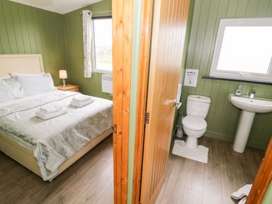 A bedroom with a bed and nightstand next to a bathroom with a toilet and sink at Cotswold View 1 in Honeybourne