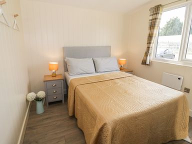 A bedroom with a double bed between two bedside tables with lamps and a window showing a car outside at Cotswold View 3 Bretforton near Evesham