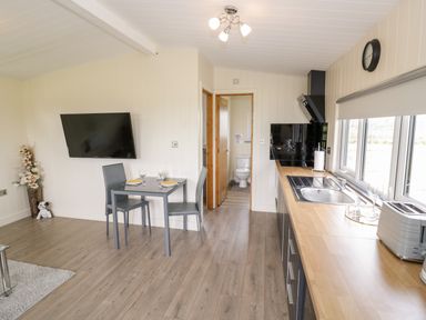 A kitchen and dining area with a table set for two and a view of a bathroom at Cotswold View 3 in Bretforton near Evesham