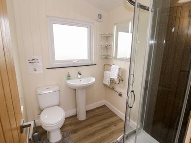 A bathroom with a toilet, pedestal sink, wall mirror, towel rack, and glass shower enclosure at Cotswold View 3 in Bretforton near Evesham