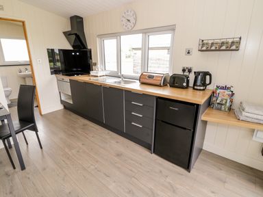 A kitchen with black cabinets a wooden countertop a fridge toaster kettle and a sink at Cotswold View 4 Bretforton near Evesham