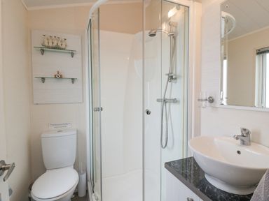 A bathroom with a toilet shower cabin mirror and sink at Oyster Bay Lodge in Dalbeattie