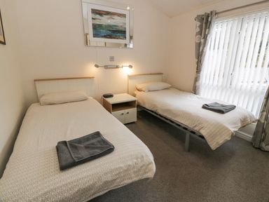 A bedroom with two single beds and a bedside table between them at Oyster Bay Lodge in Dalbeattie