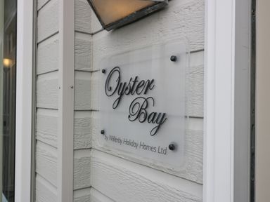 A sign reading Oyster Bay by Willerby Holiday Homes Ltd mounted on exterior wall