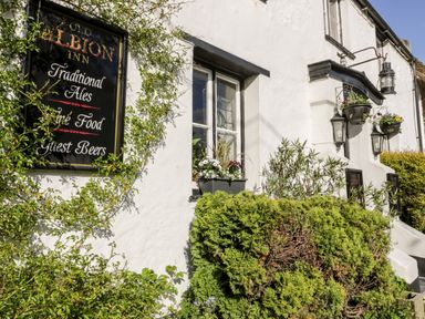 The exterior of a white building with a sign for the old albion inn traditional ales fine food guest beers and plants around the window