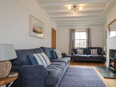 A sitting room with two blue sofas a patterned rug a lamp and a fireplace at Tresawle in Crantock