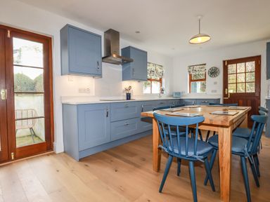 A kitchen with blue cabinets wooden dining table and blue chairs at Tresawle in Crantock