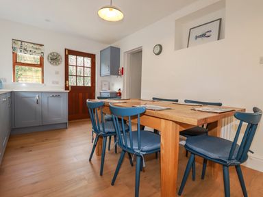 A kitchen dining area with blue chairs around a wooden table and blue kitchen cabinets at Tresawle in Crantock