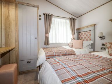 A bedroom with two single beds by a window and a wooden wardrobe at Beachcliff in Porth