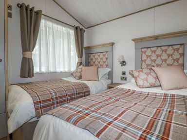 A bedroom with two single beds featuring patterned headboards and plaid blankets at Beachcliff in Porth