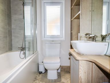 A bathroom with a bathtub shower toilet and sink at Beachcliff Porth